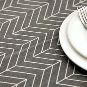 Macro detail of grey chevron pattern linen-cotton tablecloth with a white plate and fork