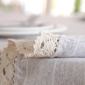 Detail of crochet lace edge on cream cotton linen tablecloth with a rustic texture