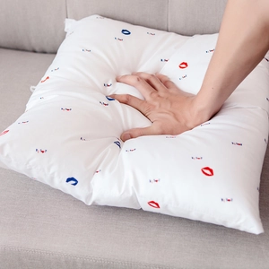 White linen pillow with tropical lip kiss print on a gray fabric sofa setup