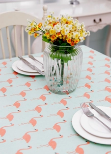 Detail of mint green flamingo print tablecloth with elegant table setting decor