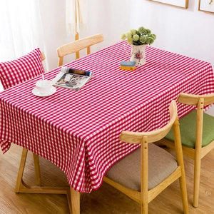 Detailed view of red and white gingham tablecloth on a wooden table with home decor
