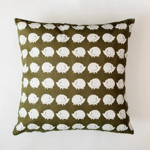 Detail of Nordic style green cushion cover featuring a white hedgehog pattern and fabric texture