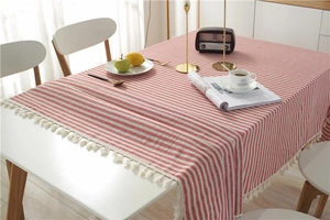 Detail of red and white striped cotton-linen tablecloth with elegant white tassels edge