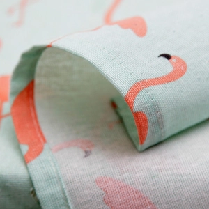 Detail of flamingo print on light green cotton linen fabric with neat edge stitching