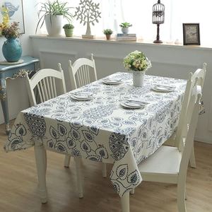 Detail of cotton canvas tablecloth with blue pineapple and leaf patterns on a white table