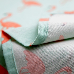 Macro detail of flamingo print tablecloth showing linen texture and edge stitching