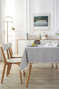 Detail of blue and white striped cotton tablecloth with elegant white fringe tassels