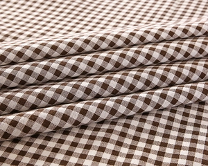 Close-up of brown and white gingham cotton fabric showing detailed weave and soft texture