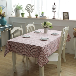 Detail of pink cotton canvas tablecloth with leaf floral patterns on a wooden dining table