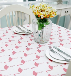 Detail of pink flamingo print on white linen blend tablecloth in a home dining setting