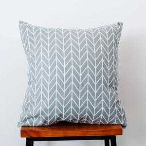 Close-up of a grey and white herringbone pillow on a minimalist wooden bench