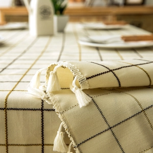Close-up of geometric plaid tablecloth with fringe tassels and woven cotton linen texture
