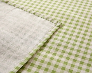 Detailed macro view of green and white checkered table cloth with durable stitched edges