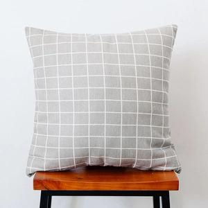 Close-up of Nordic grey and white checkered pillowcase on a modern wooden stool