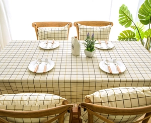 Detailed close-up of woven cream tablecloth with black grid pattern and tassel edge fringe