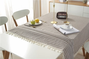 Close-up of brown and beige striped cotton tablecloth with elegant white fringe details