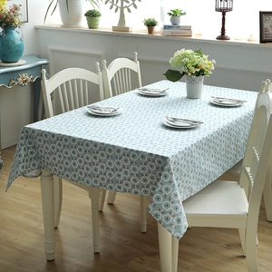 Detail of light blue cotton canvas tablecloth with white floral pattern on a dining table