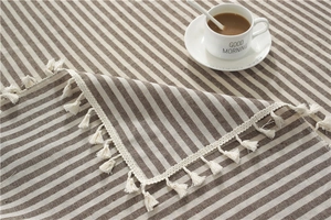 Detailed texture of coffee-colored striped cotton linen tablecloth with tassel fringe