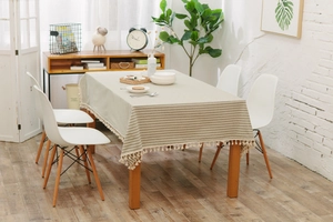 Detail of grey and beige striped tablecloth featuring elegant white tassel edges