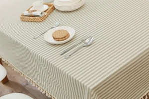 Close-up of light green striped cotton linen tablecloth with decorative white fringe edges