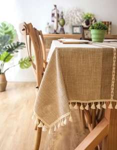 Detailed macro view of beige jacquard tablecloth with leaf embroidery and fringe tassels