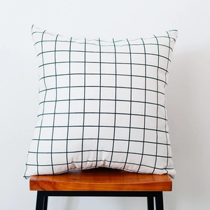 Detail shot of Nordic checkered cotton linen cushion with green grid pattern on wooden chair