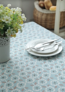 Close-up of light blue cotton tablecloth featuring small white flowers and leaves pattern
