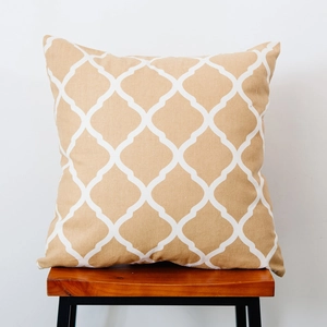 Close-up of khaki Nordic plaid throw pillow with white geometric pattern on a wooden stool