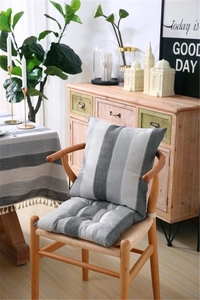 Close-up of grey and white striped linen chair cushion with tassels on a wooden chair