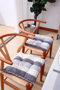 Detail of striped gray and white quilted seat cushions on wooden chairs in cozy setting