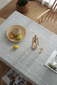 Close-up of gray grid tablecloth with white hand-stitched knots and rustic wood texture