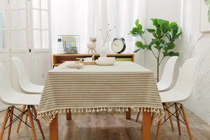 Detail of grey and light brown striped tablecloth with white pom-pom tassel edges