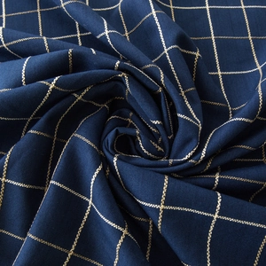 Macro detail of dark blue jacquard tablecloth featuring fine golden windowpane patterns