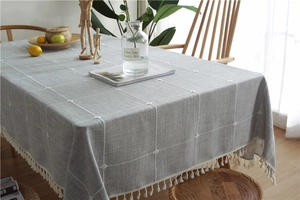 Close-up of gray plaid linen tablecloth featuring elegant white tassels and diamond texture