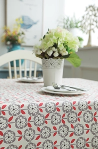 Close-up of minimalist cotton canvas tablecloth with gray flowers and red leaf patterns
