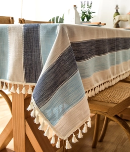 Detail view of striped waterproof table cloth with fringe tassels on a wooden table