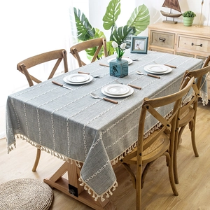 Detail of grey-blue cotton linen tablecloth with geometric white stripes and tassels