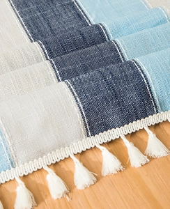 Macro detail of navy blue and sky blue striped linen tablecloth with white cotton tassels