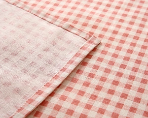 Close-up of red and white checkered tablecloth fabric with detailed edge stitching