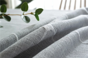 Detailed macro view of gray cotton linen tablecloth with white embroidery and fringe