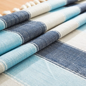 Close-up of waterproof striped linen tablecloth with tassel fringe and geometric blue weave