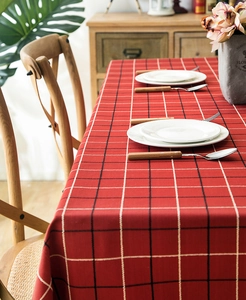 Detail of red plaid waterproof tablecloth featuring geometric fringe on a wooden table