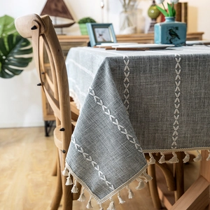 Detail of grey linen tablecloth with white embroidery lines and tassel fringe edges