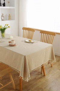 Close-up of yellow and white striped cotton table cloth with delicate tassel edge detail