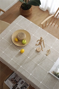 Close-up of linen tablecloth featuring embroidered floral grid and tassel fringe details