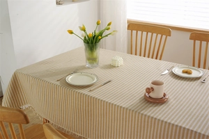 Close-up of yellow and white striped cotton-linen tablecloth with white fringe lace edge