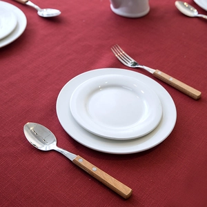 Close-up of polished stainless steel cutlery with wooden handles and double rivets on a red cloth