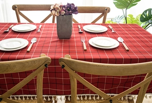 Detail of red checkered tablecloth featuring white tassel fringe and jacquard texture