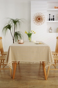 Close-up of beige striped polyester-cotton tablecloth with white fringe in a modern room