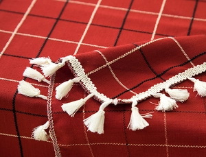 Detail of red and black plaid tablecloth featuring high-quality white tassel fringe edge